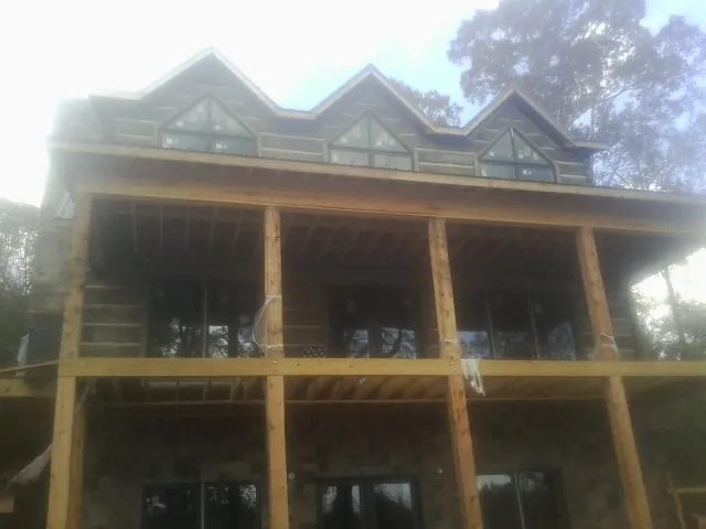 Dormers and porch framing on a large log home under construction in Bedford